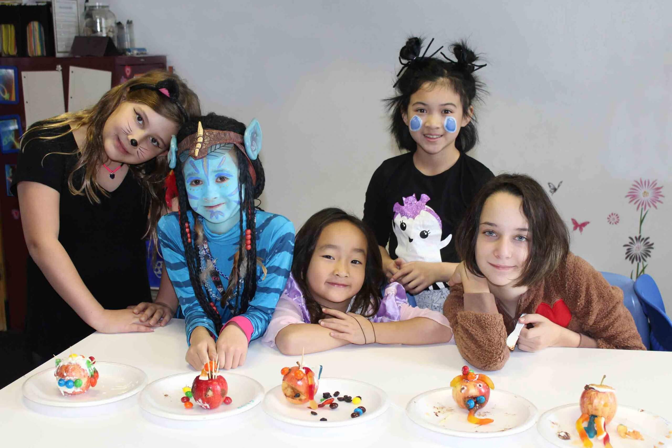 Elementary students posing with their Halloween costume around a table