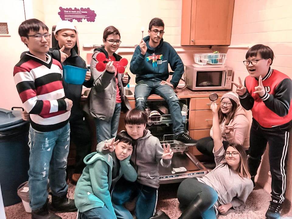 Students sit around the dishwasher in new kitchen
